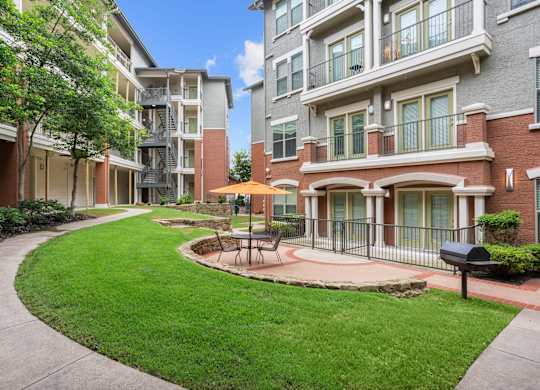 A sunny day at a residential complex with a green lawn and a small fountain.