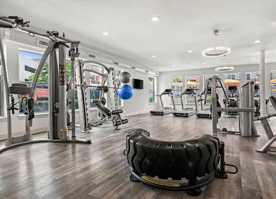 A gym with a variety of equipment including treadmills, weights, and exercise machines.