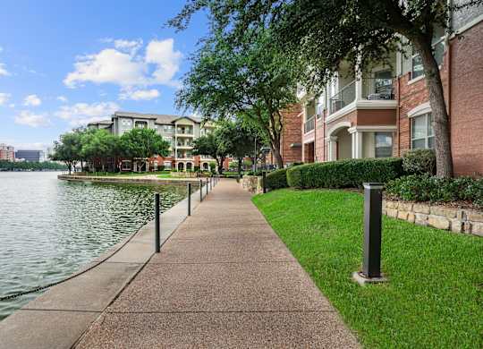 A walkway next to a body of water with a building in the background.