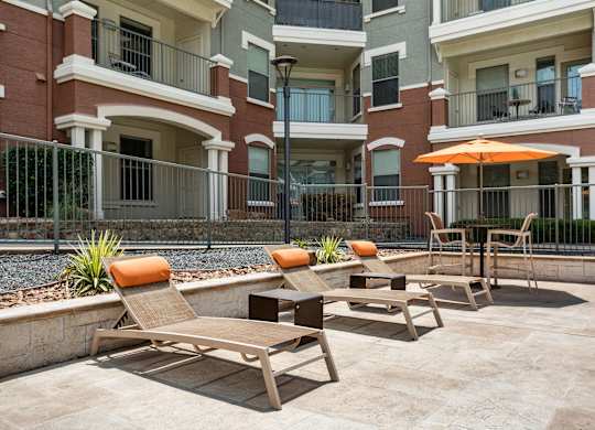 A patio with chairs and an umbrella in front of a building.
