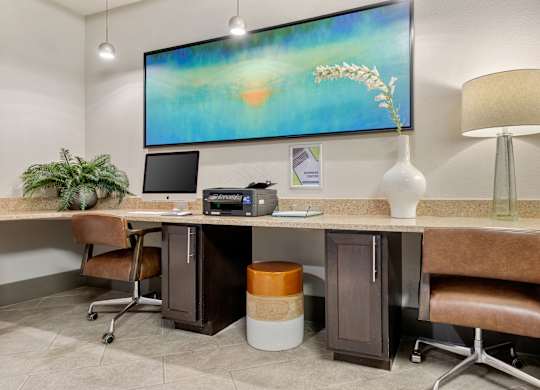 A modern office with a large screen on the wall and a desk with a chair and a plant.