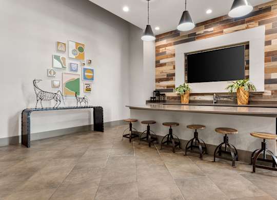 A modern bar area with a wooden wall and a bench with a cow print.