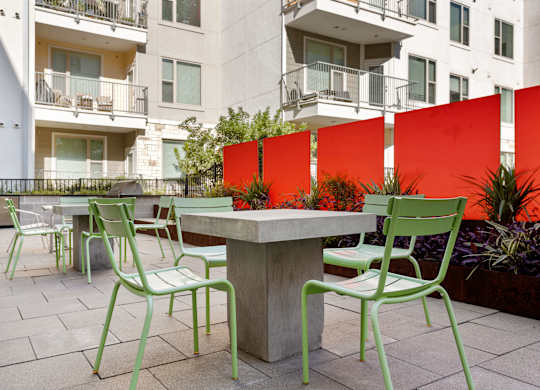 Green chairs and table in front of a red wall.