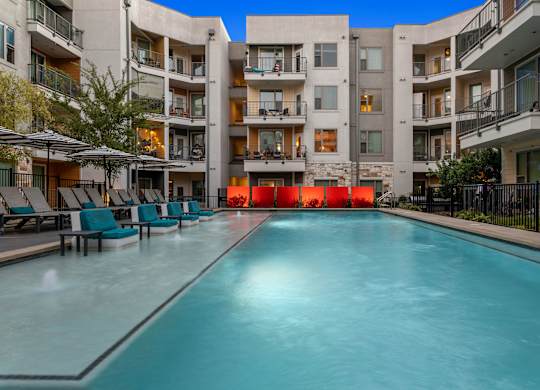 A long rectangular pool in front of apartment buildings.