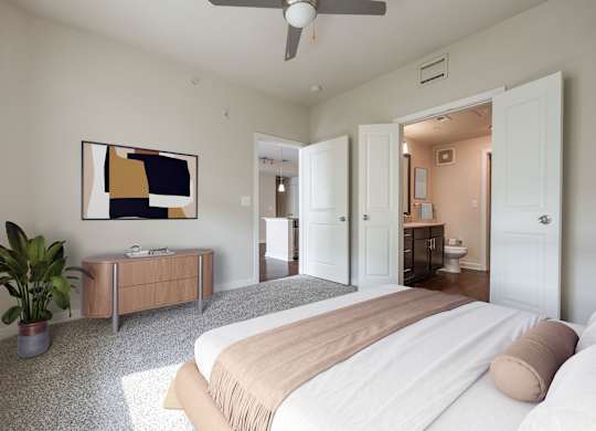 A bedroom with a bed, a plant, and a painting on the wall.