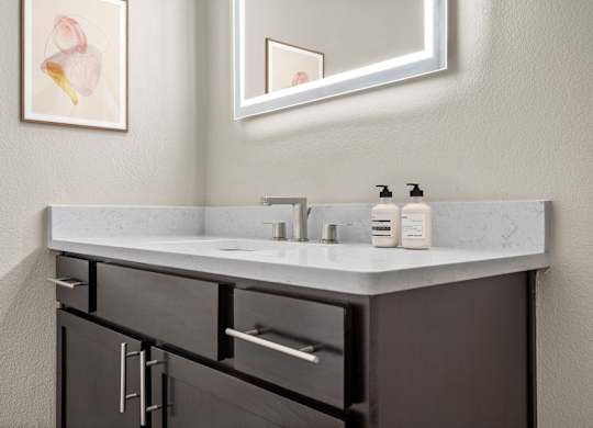 A bathroom with a sink, mirror, and cabinets.
