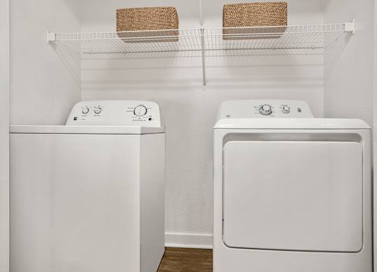 Two white front loading washing machines in a laundry room.