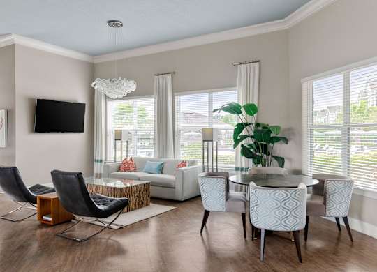 A modern living room with a white sofa, a glass coffee table, and a TV mounted on the wall.