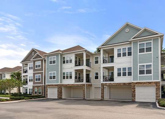 A large, modern apartment building with multiple garages and balconies.