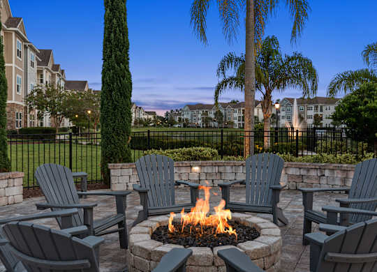 A fire pit surrounded by Adirondack chairs in a backyard.