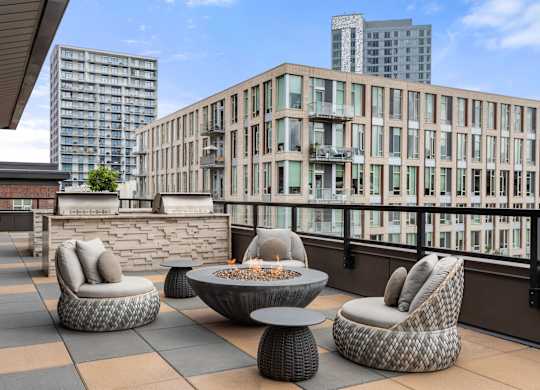 A patio with a fire pit and chairs.