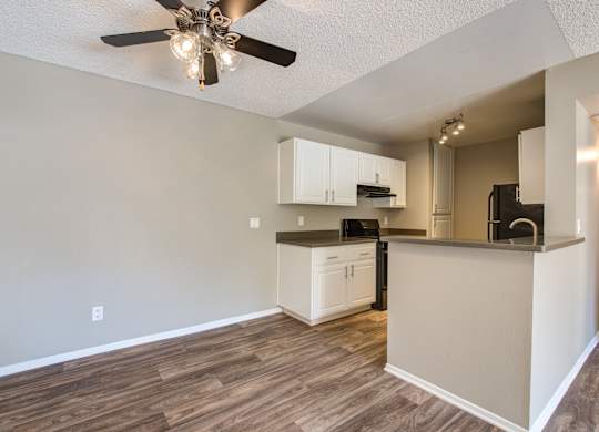 A kitchen with a ceiling fan and wooden floors.
