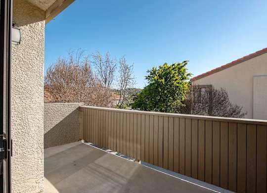 A balcony with a beige railing and a concrete floor.