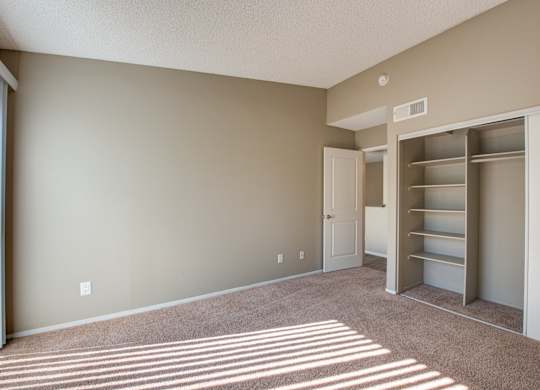 A room with a carpeted floor and a white door leading to another room.