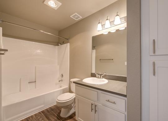 A white bathroom with a toilet, sink, and mirror.