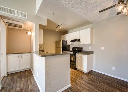 A kitchen with white cabinets and a wooden floor.