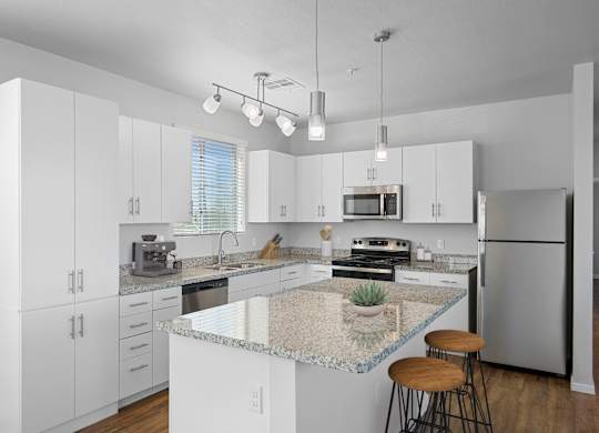 A kitchen with white cabinets and a granite countertop.