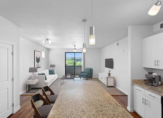 A well-lit, modern living room with a large window and a kitchen area.