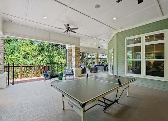 A ping pong table is in the middle of a room with a ceiling fan.