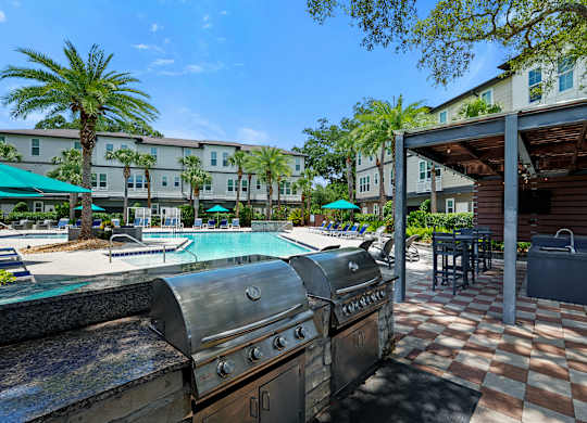 A BBQ grill is in the foreground of a resort style pool area.