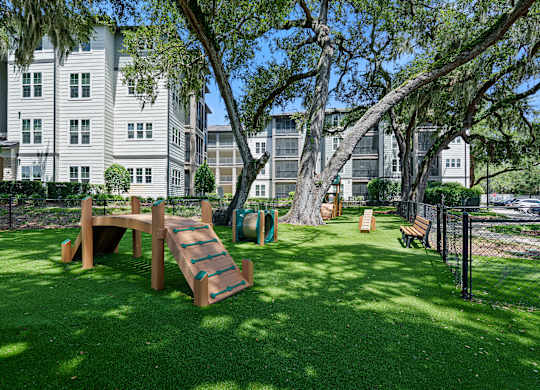 A playground with a slide and a wooden bench is in the foreground of a grassy area.