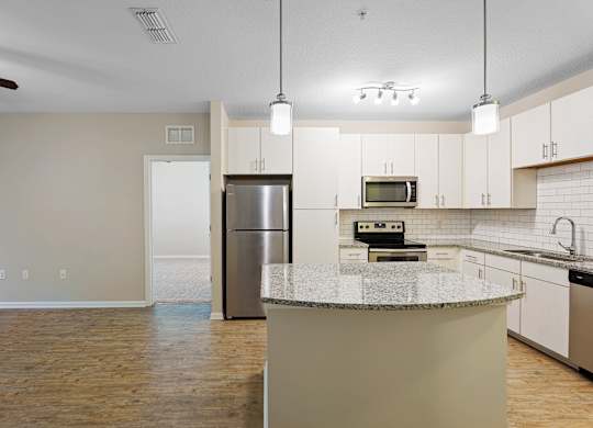 A kitchen with a refrigerator, microwave, and oven.