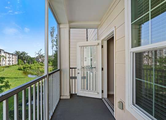 A balcony with a view of a green lawn and buildings.