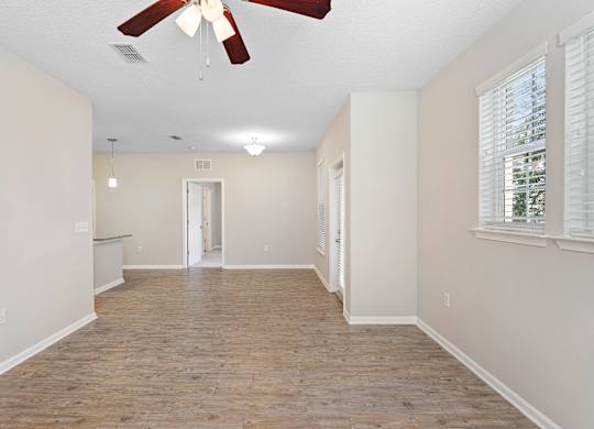 A room with a ceiling fan and wooden flooring.