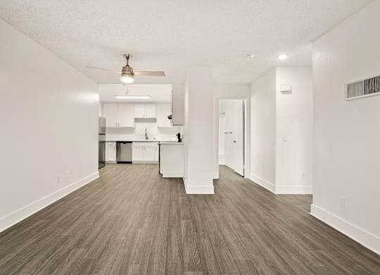 A kitchen with white cabinets and a wooden floor.