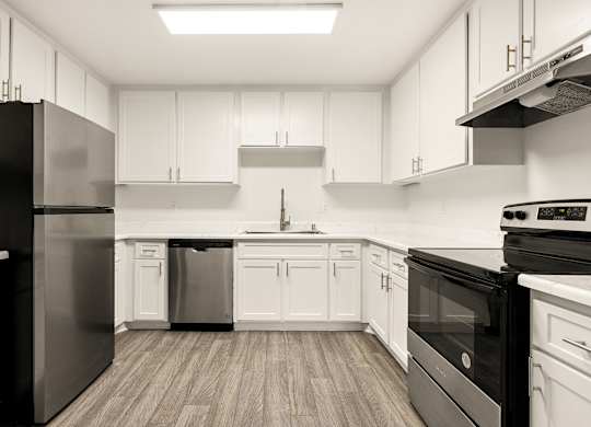 A modern kitchen with black appliances and white cabinets.