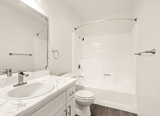 A white bathroom with a marble counter top and a white toilet.