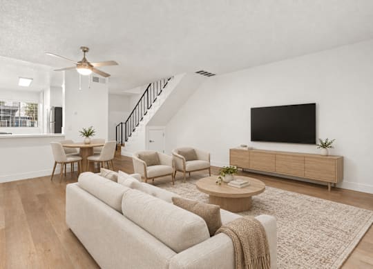 A living room with a beige couch, a coffee table, and a flat-screen TV.