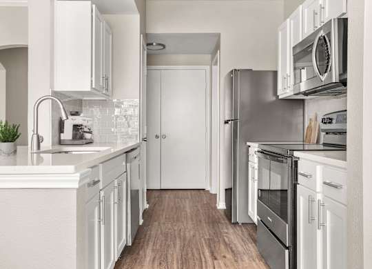 A modern kitchen with white cabinets and stainless steel appliances.