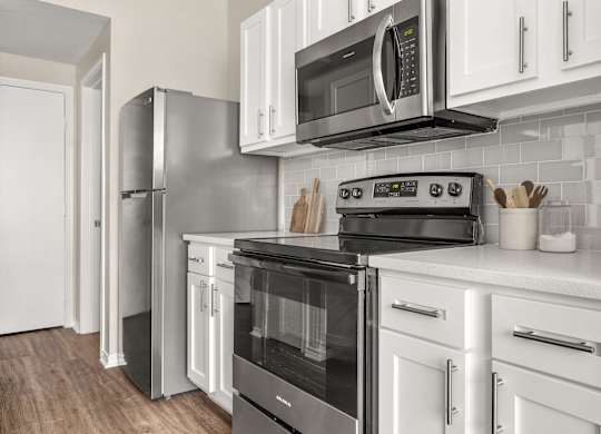 A modern kitchen with white cabinets and stainless steel appliances.