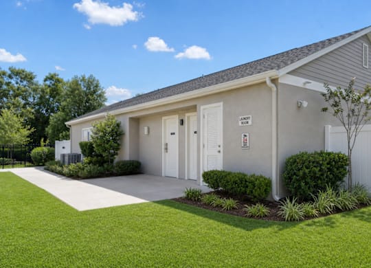 A small building with a grey roof and white walls has a sign on it.