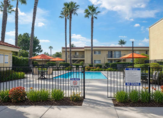 A pool surrounded by a black fence with a sign that says "No Diving".