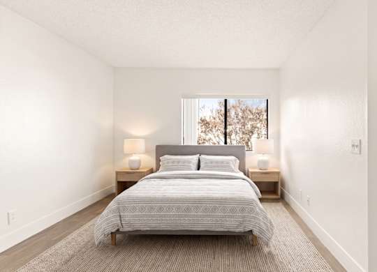 A bedroom with a large bed and two lamps.
