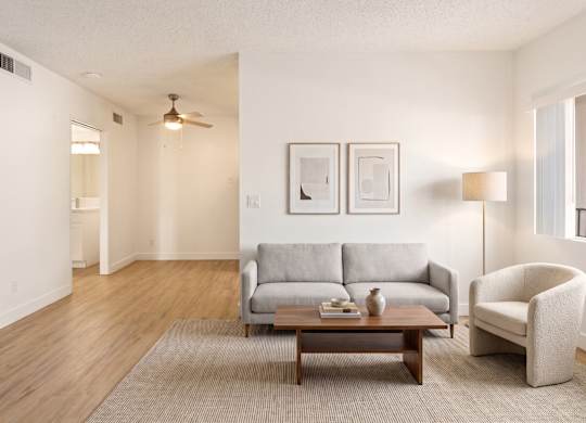 A living room with a grey couch, a brown coffee table, and a white chair.