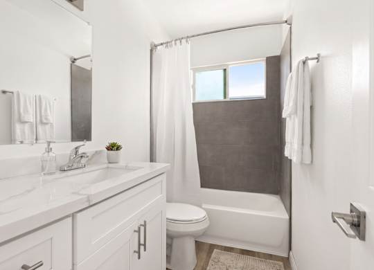 A white bathroom with a toilet, sink, and bathtub.