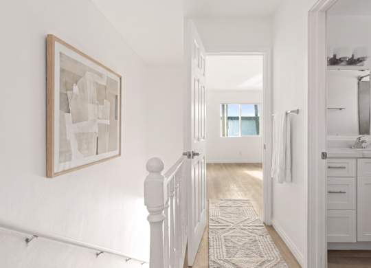 A hallway with a rug and a painting on the wall.