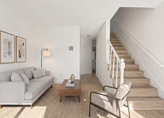 A living room with a couch, chair, and stairs.