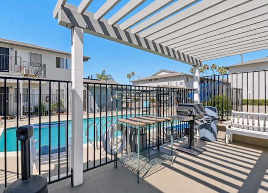 A pool area with a white pergola and black fence.