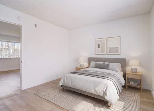 A bedroom with a bed, nightstands, and pictures on the wall.