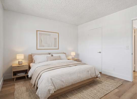 A bedroom with a large bed and two nightstands.