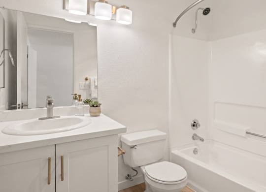 A white bathroom with a toilet, sink, and bathtub.