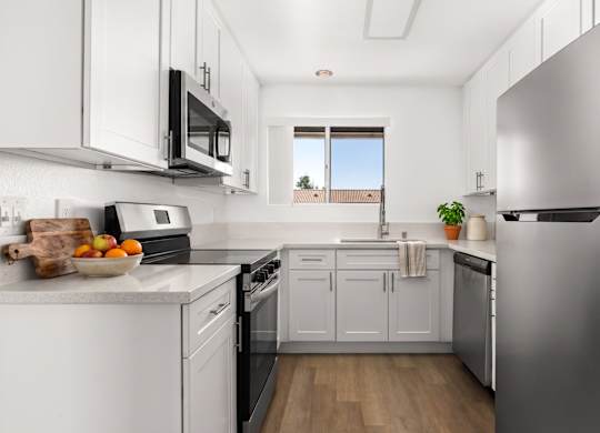 A kitchen with white cabinets and a stainless steel refrigerator.