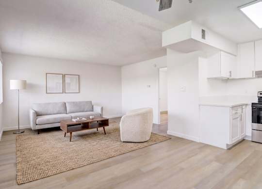 A living room with a grey couch, a white chair, and a wooden coffee table.