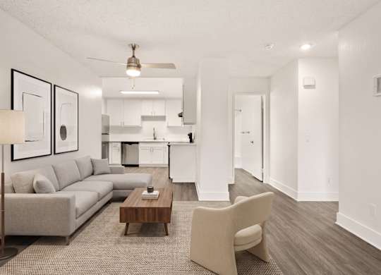 A modern living room with a grey sofa, a wooden coffee table, and a beige armchair.