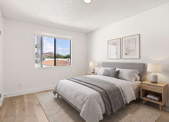 A bedroom with a large bed and a window overlooking a street.