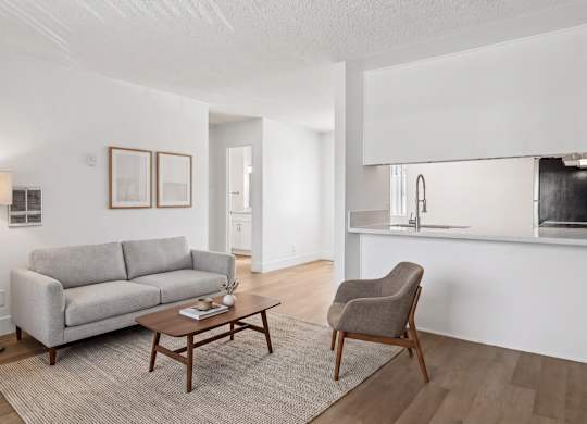 A living room with a grey couch, a brown chair, and a wooden coffee table.